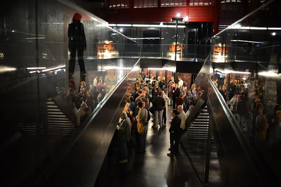 Vue intérieure du Rocher de Palmer à Cenon montrant une foule de visiteurs dans un espace moderne avec escaliers, éclairage architectural et vitrines illuminées.