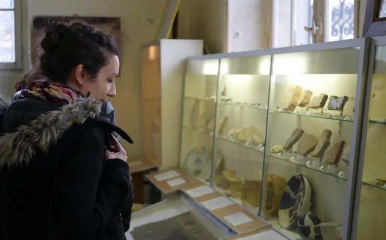 Une femme observe des vitrines d'exposition contenant des artefacts archéologiques et objets historiques au Musée des Amis du Vieux Lormont à Bordeaux.