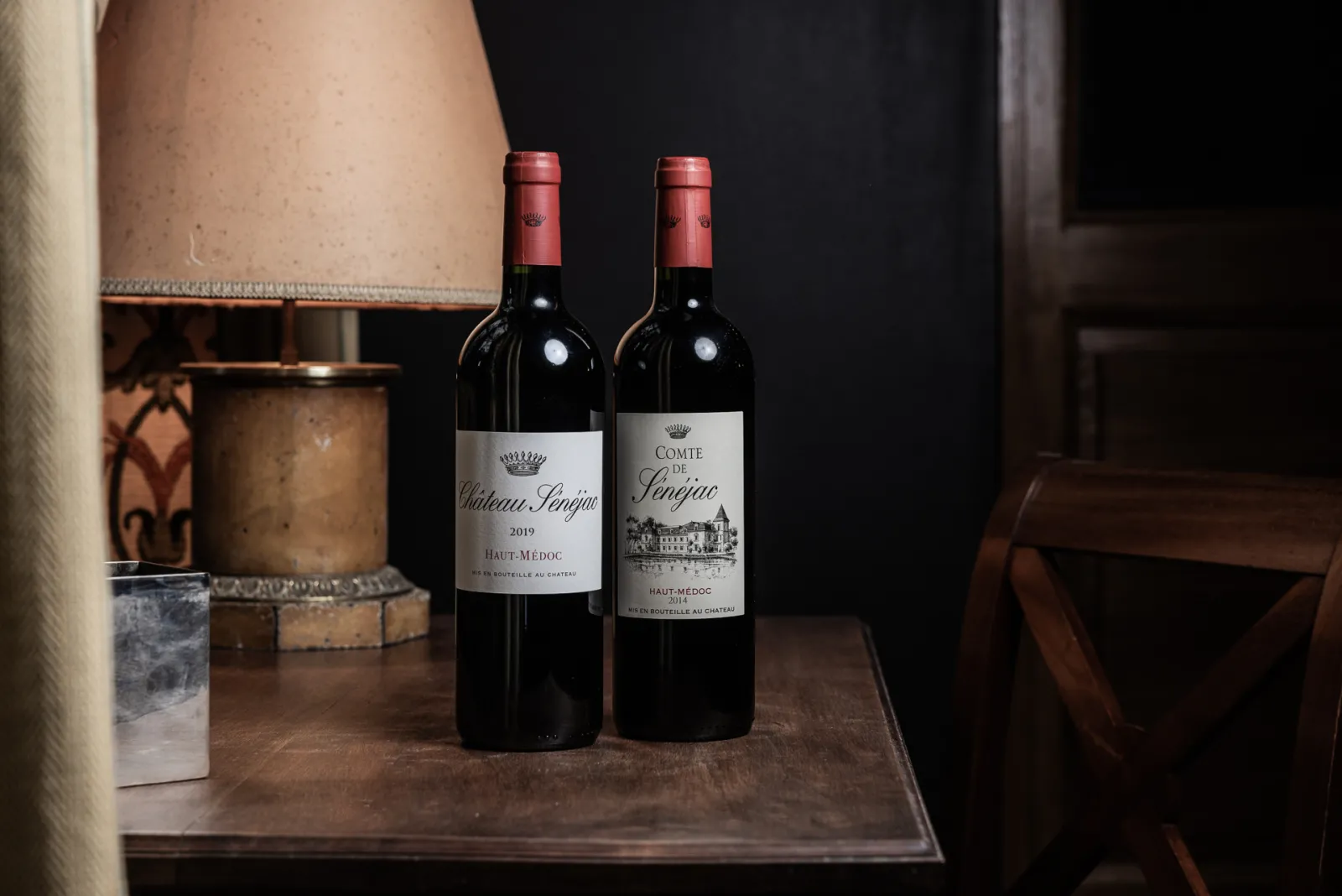 Deux bouteilles de vin rouge Haut-Médoc du Château Sénéjac et du Comte de Pongac posées sur une table en bois, dans un intérieur élégant à Bordeaux.
