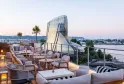 Terrasse panoramique du Renaissance Bordeaux Hôtel au coucher du soleil, avec mobilier design, vue sur la Garonne et l'architecture contemporaine de la ville.
