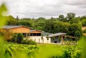 Le Château de Malherbes près de Bordeaux, une bâtisse architecturale moderne en bois et pierre entourée de vignes et de végétation luxuriante.