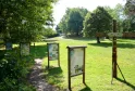 Panneaux d'information pédagogique disposés dans un parc verdoyant du site de Moulin Bidon à Bordeaux, avec des arbres et un équipement en bois au premier plan.
