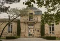Façade en pierre d'une élégante demeure bordelaise avec balcon à balustrade, encadrement symétrique de cyprès, et gravier blanc en avant, dans le quartier de Cordeillan à Bordeaux.