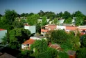 Vue aérienne de la Cité Frugès à Pessac, ensemble de maisons modernistes de Le Corbusier aux façades colorées (orange, blanc, vert clair) entourées de végétation luxuriante.