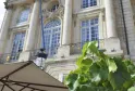 Façade néoclassique du Palais de la Bourse de Bordeaux avec colonnes blanches, fenêtres à meneaux et décorationsculptées, vue de la terrasse avec parasol et plantes vertes