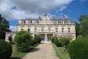 Façade du Château Tayac à Bordeaux, édifice néoclassique du XIXe siècle avec mansardes, balustrades et ornementation sculptée, accès par une allée de gravier bordée de végétation