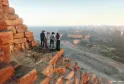 Quatre personnes observent la vue panoramique de Bordeaux depuis une fortification en pierre rouge surplombant la ville, la Garonne et les bâtiments historiques en arrière-plan.