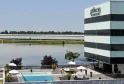 Vue de l'hôtel Pullman Bordeaux Lac avec sa façade rayée blanc et noir, surplombant une piscine et un lac, avec des espaces verts en arrière-plan