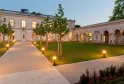 Cour intérieure illuminée de La Table de La Chèze à Bordeaux avec bâtiments en pierre, allée pavée, pelouse verte et arbres
