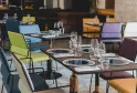 Salle de restaurant élégante avec tables dressées, chaises colorées aux tons bleu, vert et bordeaux, verres et couverts disposés, décoration épurée dans un hôtel à Bordeaux