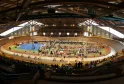 Vue panoramique du vélodrome de Bordeaux avec piste cycliste ovale, spectateurs en tribunes, et installations sportives intérieures sous structure métallique.