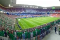 Vue intérieure du Stade Atlantique Bordeaux Métropole rempli de spectateurs en tenues vertes et rouges, avec le terrain de football visible au centre et les tribunes surpeuplées.