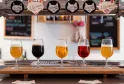 Cinq verres de dégustation alignés présentant différentes bières de la Brasserie Burdigala à Bordeaux, avec des robinets à tête de renard en arrière-plan.