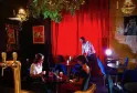 Intérieur du Théâtre des Chartrons à Bordeaux avec trois personnes dans un bar élégant aux murs rouges, éclairage chaleureux et décoration vintage.