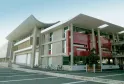 Le Carré, bâtiment moderne avec façade rouge et blanche, colonnes béton apparentes et toiture courbe, situé à Saint-Médard-en-Jalles près de Bordeaux, avec vélos garés en façade.