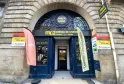 Devanture du bureau de change Monex Exchange situé à Bordeaux, rue Victor Hugo, avec portes bleues ornées de motifs dorés, enseigne jaune et affiches publicitaires Western Union et MoneyGram.